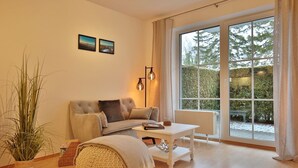 Un salon confortable avec un canapé, une petite table et une grande fenêtre donnant sur les arbres.
