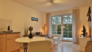 Un salon moderne avec un coin repas, de grandes fenêtres et une vue sur la verdure.