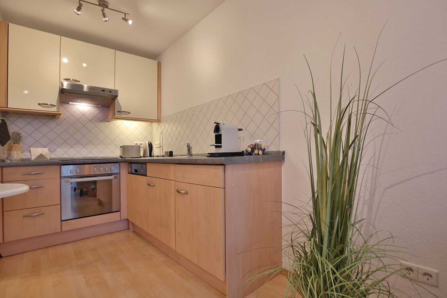 Una cocina moderna con armarios de madera, electrodomésticos de acero inoxidable y salpicadero de azulejos.