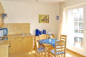 A small kitchen with wooden cabinets, a sink, and a dining area with a table and chairs.