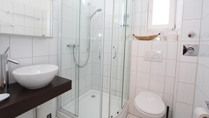 A modern bathroom with a glass-enclosed shower, a white sink, and a toilet.