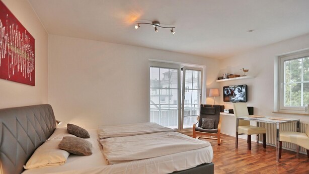 A modern hotel room with a large bed, a desk, and a chair.