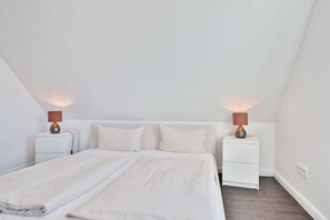 Un dormitorio con una cama grande, dos mesitas de noche y dos lámparas.