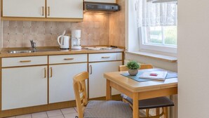 A compact kitchen with a coffee maker, a kettle, and a window with a view.