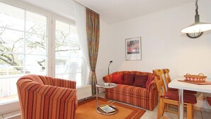 A living room with striped sofas, a small table, and a dining table with chairs.
