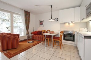 A compact living space with a dining area, kitchenette, and a sofa. - Parkblick Apartment 5 - Haus Parkblick (Scharbeutz)