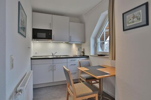 A compact kitchen with white cabinets, a microwave, and a window above the sink.