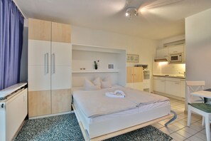 Une chambre comprenant un lit, un bureau, une chaise, un coin cuisine et une salle de bain.