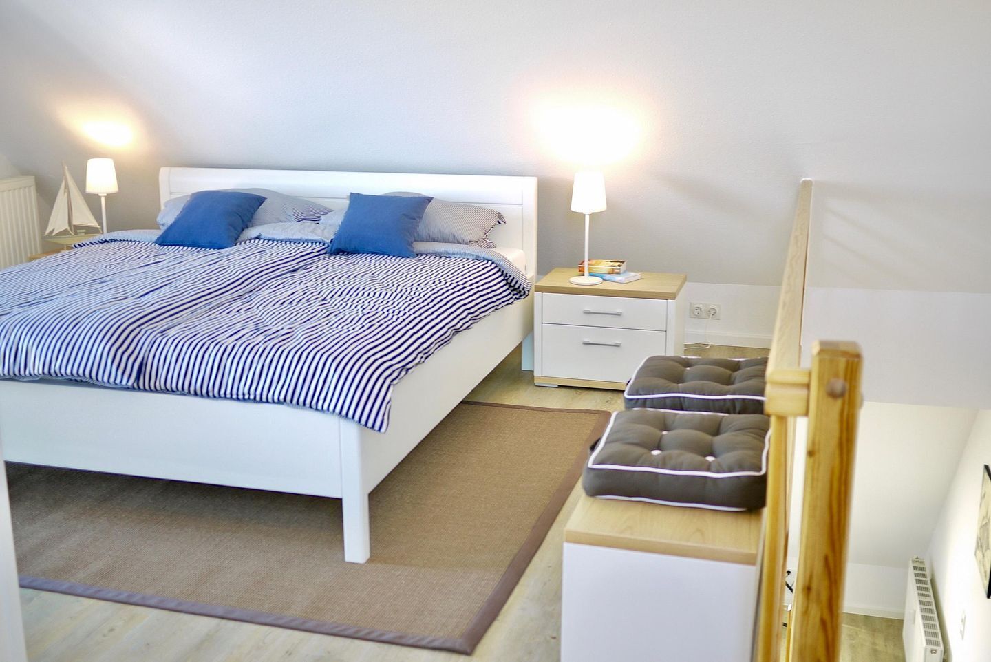 A neatly arranged bedroom with a bed, bedside tables, a nightstand, and a small stool.