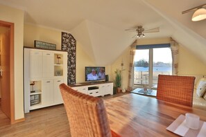 Una sala de estar acogedora con televisor, una mesa de comedor y vistas al exterior.