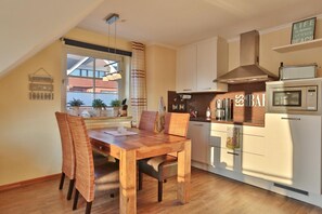 Una cocina moderna con una mesa de comedor de madera, armarios blancos y un microondas empotrado.