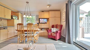 Eine moderne Küche mit Holzschränken, einem Esstisch mit Stühlen, einem Fernseher und einem großen Fenster.