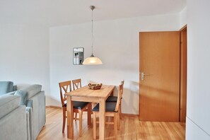 Un espacio habitable pequeño con una mesa de comedor, sillas, un sofá y una puerta de madera.