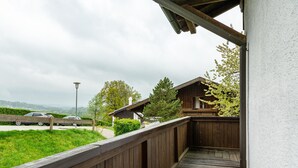 A wooden deck with a view of a road and a building with a sloped roof. - Comfort apartment with pool, sauna and Wi-Fi (Hauzenberg)