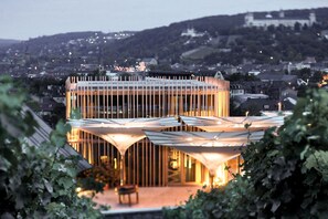 Un edificio moderno con un diseño geométrico singular, rodeado de vegetación.