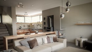 Un salon moderne avec un canapé, une table basse et un coin repas, la cuisine étant visible au fond.
