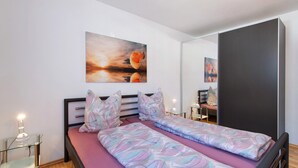 Ein Schlafzimmer mit einem Bett, Nachttischen, einem Spiegel und einem Bild an der Wand.