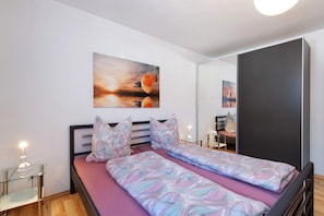 Une chambre à coucher avec un lit, des tables de chevet, un miroir et un tableau accroché au mur.
