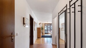 Ein Flur mit einer Holztür, einem Lichtschalter und einem gerahmten Bild an der Wand.