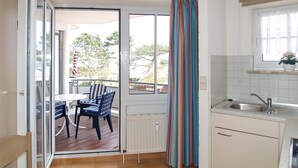 A kitchen with a window, a dining area with a table and chairs, and a view of the outdoors.
