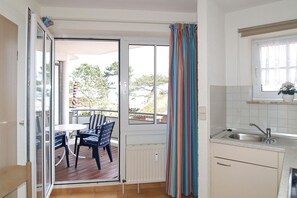Una cocina con ventana, un comedor con mesa y sillas, y vistas al exterior.