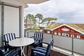 Un balcón con mesa y sillas, con vista a un edificio rojo con un letrero que dice "GOSCH".