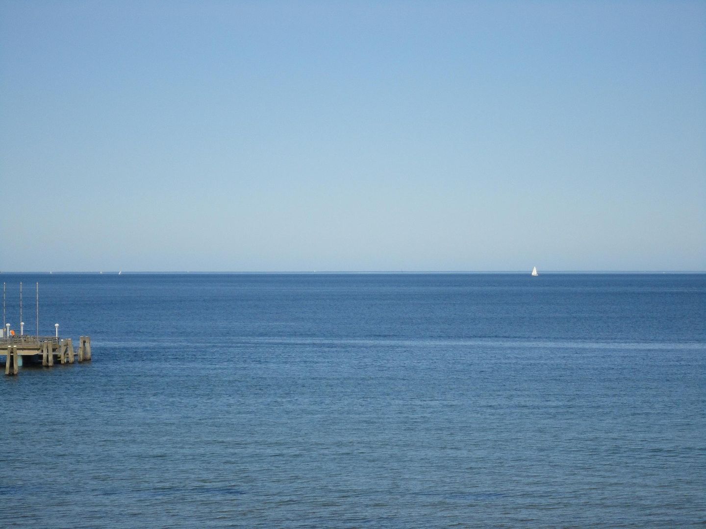 Une mer calme avec une jetée qui s’avance dans l’eau.