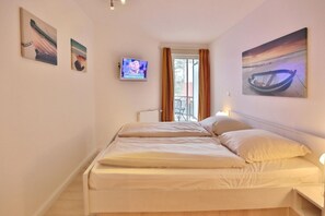Une chambre d’hôtel avec un lit, une télévision et des œuvres d’art accrochées aux murs.