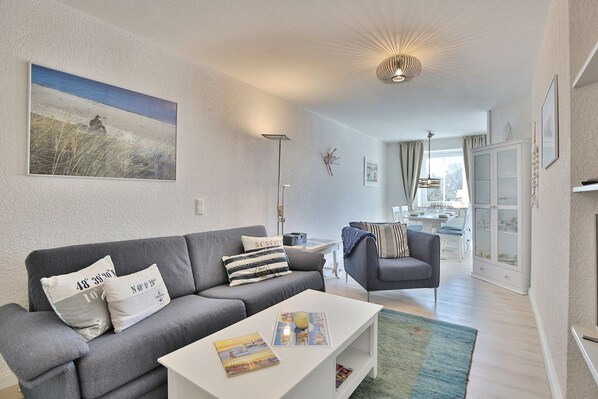 Ein modernes Wohnzimmer mit grauem Sofa, weißem Couchtisch und einem Bild an der Wand.