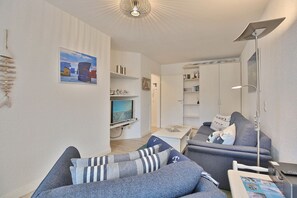 Un salon moderne avec un canapé gris, un téléviseur à écran plat et une bibliothèque.