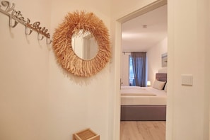 Une chambre à coucher comprenant un lit, une table de chevet, un miroir et un luminaire fixé au mur.