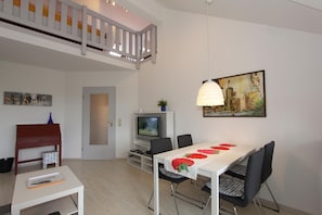 Una sala de estar moderna con comedor, televisor y un cuadro en la pared.