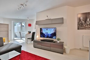 Una sala de estar moderna con un televisor de pantalla plana, un sofá gris y una alfombra roja.