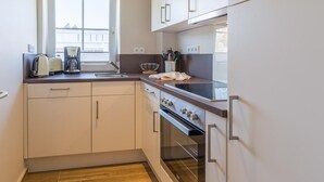 Une cuisine de taille réduite, dotée d’une fenêtre, d’une cuisinière et d’un évier.