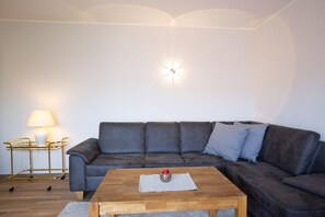 Un salon comprenant un canapé, une table basse, une lampe et un luminaire en forme d’étoile fixé au mur.