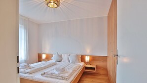 Une chambre à coucher moderne avec un lit en bois, deux tables de chevet avec des lampes et une armoire en bois.