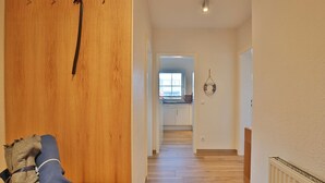 Un couloir mène à une cuisine dont le sol est recouvert de parquet et où se trouve un radiateur sur le côté droit.