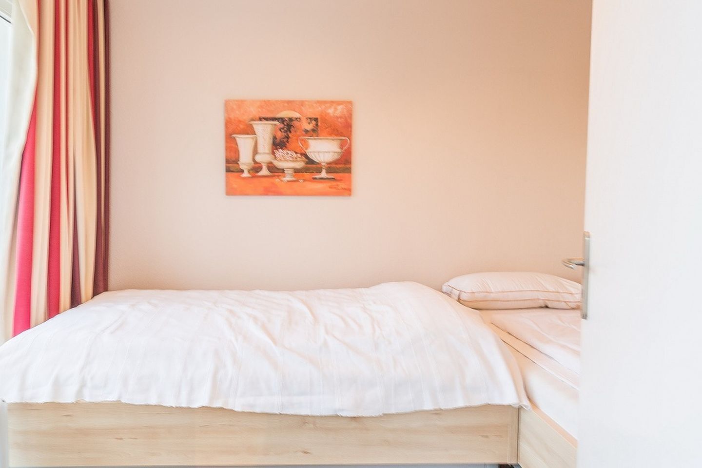 A bedroom with a bed, a pillow, and a painting on the wall.