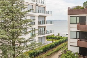 Un immeuble résidentiel moderne à plusieurs étages, doté de balcons donnant sur un plan d’eau.