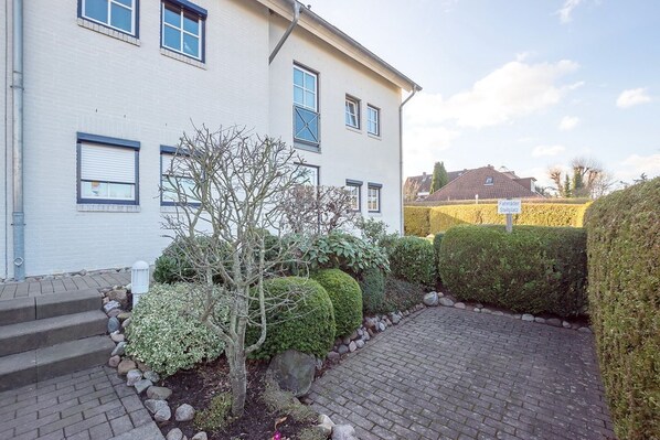 A two-story building with a paved driveway and a well-maintained garden.