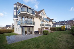 A modern two-story house with a balcony, a patio, and a well-maintained lawn.