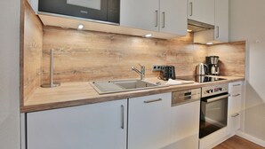 Eine moderne Küche mit integriertem Mikrowellenherd, Edelstahlgeräten und Holzkorpussen.