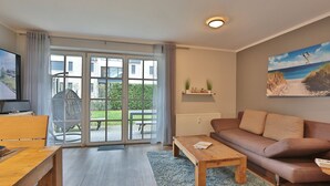 Ein modernes Wohnzimmer mit einer Couch, einem Couchtisch und einem Fernseher auf einem Holztisch.