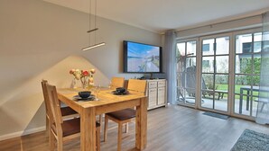 Ein Essbereich mit Holztisch, Stühlen und einem Fernseher an der Wand.