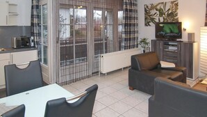 A modern living room with a dining area, a kitchen, and a TV. - Baltic Sea view apartment 3 - Baltic Sea view (Scharbeutz)