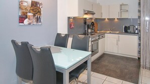 A compact kitchen with a dining table and chairs, a microwave, a stove, and a sink. - Baltic Sea view apartment 3 - Baltic Sea view (Scharbeutz)