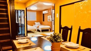 A hotel room with a dining area, a bed, and a bathroom visible through an open door. - Art House  (東大阪市足代)