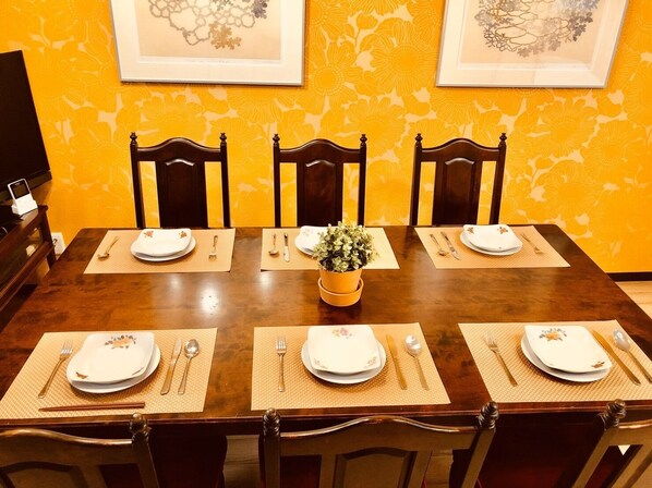 A dining table set for six with placemats, plates, cutlery, and a centerpiece.