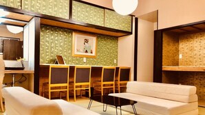 A traditional Japanese-style living room with tatami flooring, a low table, and a sofa. - Art House  (東大阪市足代)