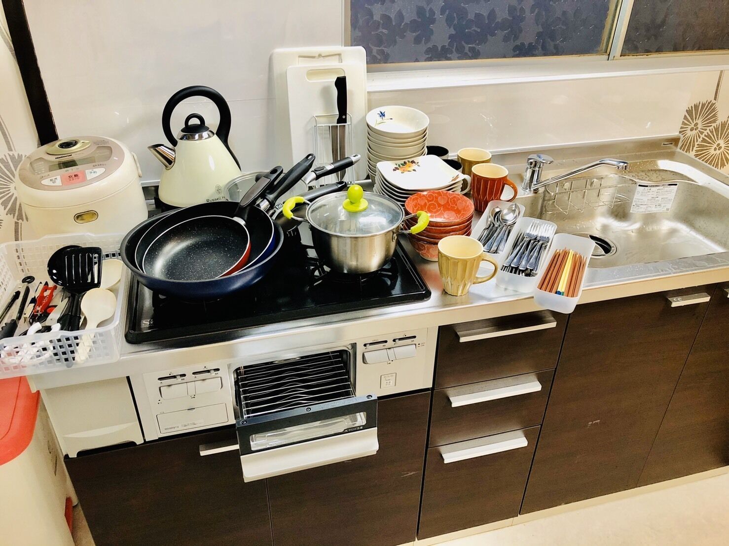A kitchen with a stove, pots, pans, and a sink.